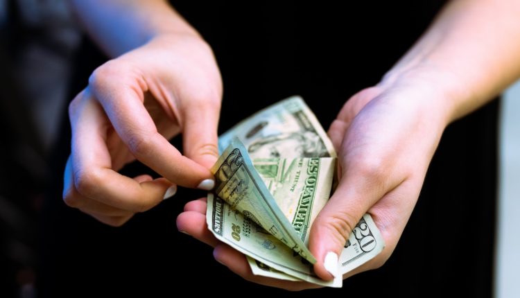 person holding fan of 100 us dollar bill