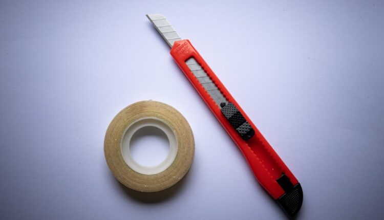 red and black click pen beside white tape roll
