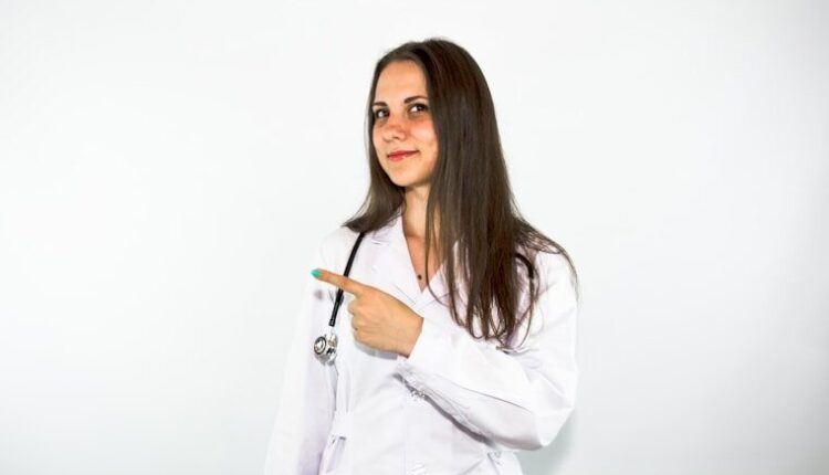 a woman in a white lab coat pointing at something